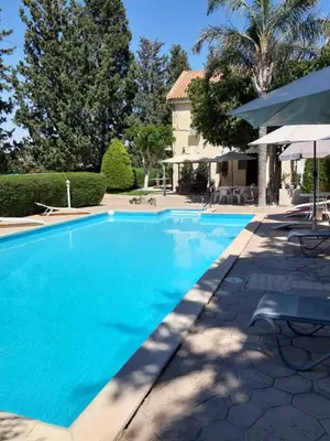 a blue swimming pool with a house and trees at Zena Holiday Villa in Pissouri