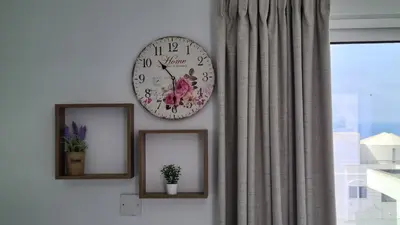 a clock hanging on a wall with two pictures at STAY Napa Living Studios in Ayia Napa