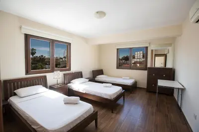 a room with two beds and two windows at Ayia Napa Holiday Apartment Na101 in Ayia Napa