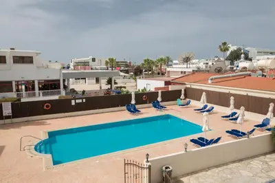 a swimming pool on the roof of a building with chairs at Ayia Napa Holiday Apartment Na101 in Ayia Napa
