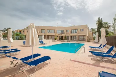a pool with chairs and umbrellas in front of a building at Ayia Napa Holiday Apartment Na101 in Ayia Napa