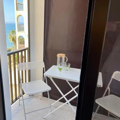 a small white table with two glasses on a balcony at Seaside Studio Zygi in Zygi