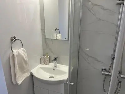 a white bathroom with a sink and a shower at Seaside Studio Zygi in Zygi
