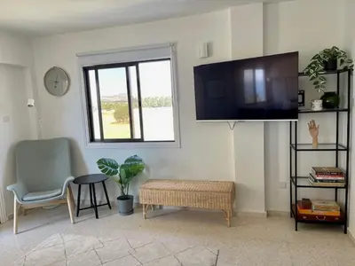 a living room with a tv and a chair at Seaside Studio Zygi in Zygi