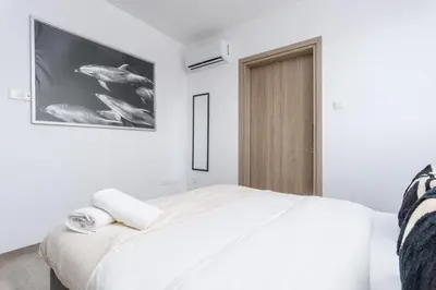 a white bedroom with a large bed and a tv at Mirage 2-BR Apartment in Larnaca in Larnaka