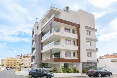 a white building with cars parked in front of it at Mirage 2-BR Apartment in Larnaca in Larnaka