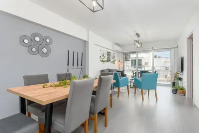 a dining room with a wooden table and blue chairs at Amore 2-BR Apt By Finikoudes in Larnaka