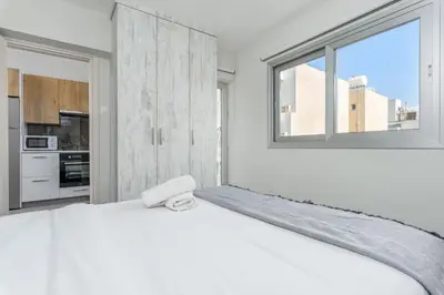a white bedroom with a large bed and a window at Amore 2-BR Apt By Finikoudes in Larnaka