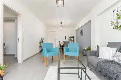 a living room with blue chairs and a couch at Amore 2-BR Apt By Finikoudes in Larnaka