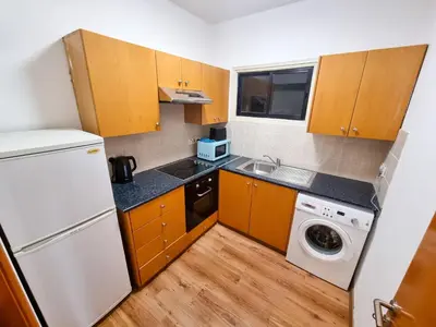 a small kitchen with wooden cabinets and a white refrigerator at CityCenter Apartment in Larnaka