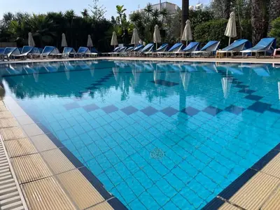 a large swimming pool with chairs and umbrellas at Giorgis Luxury Apartments in Ayia Napa