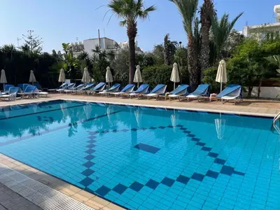a large swimming pool with chairs and umbrellas at Giorgis Luxury Apartments in Ayia Napa