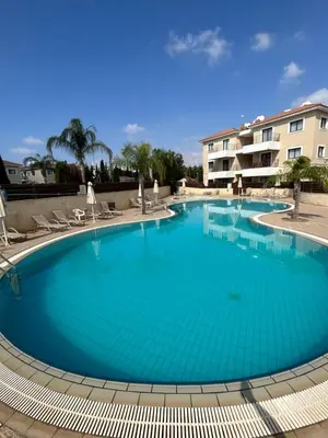 a large blue swimming pool with chairs and a building at Antiparos 1 bedroom APT Kyklades in Paralimni
