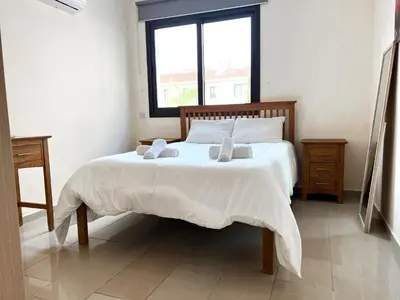 a bedroom with a bed with two pillows and a window at Paros 1 bedroom APT Kyklades in Paralimni