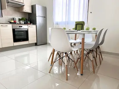 a kitchen with a table with white chairs and a laptop at Paros 1 bedroom APT Kyklades in Paralimni