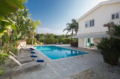 a swimming pool with lounge chairs next to a house at Papaya Royal Villa in Ayia Napa
