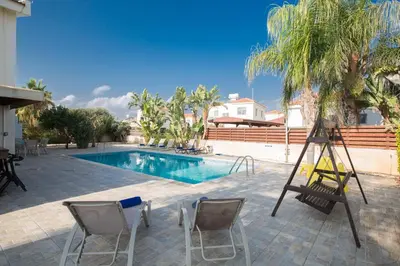 a pool with two chairs and a ladder next to it at Papaya Royal Villa in Ayia Napa