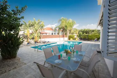 a patio with a table and chairs next to a swimming pool at Papaya Royal Villa in Ayia Napa