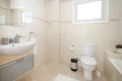 a white bathroom with a sink and a toilet at Villa Adonia - 30m from Pernera Beach in Protaras