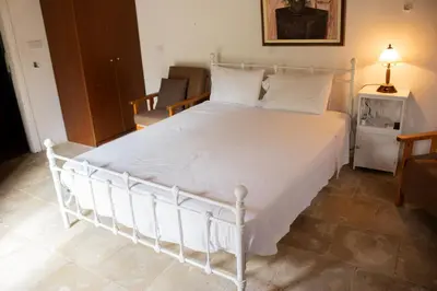 a large white bed in a room with a chair at Morfeas Kakopetria in Kakopetria