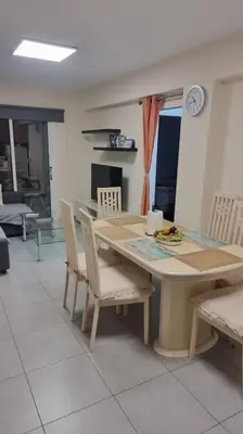 a dining table and chairs in a kitchen with a clock at Mezzarina apartment ayia napa in Ayia Napa