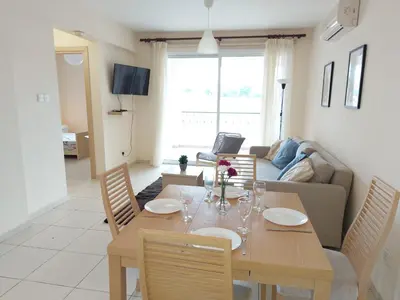 a living room with a wooden table and chairs at Pyla Palms Resorts A2 102 in Pyla