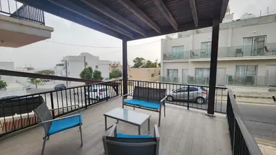 a balcony with chairs and a table and a car on a street at Cozy studio with terrace, sea views, near beaches and amenities in Ayia Napa