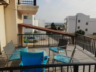 a balcony with two blue chairs on a balcony at Cozy studio with terrace, sea views, near beaches and amenities in Ayia Napa