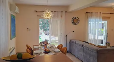 a dining room with a table and a couch at VILLA MARINA BY FIG TREE BAY in Protaras