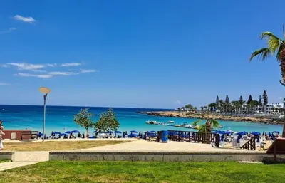 a beach with blue chairs and the ocean at VILLA MARINA BY FIG TREE BAY in Protaras