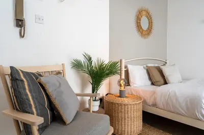 a bedroom with a bed and a chair and a mirror at Orchid's Cozy Studio & Balcony in Larnaca in Larnaka