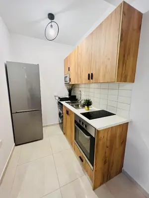 a kitchen with wooden cabinets and a stainless steel refrigerator at LINA 25 in Larnaka