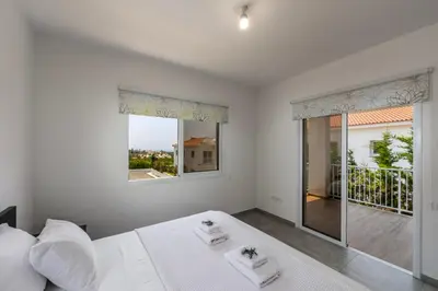 a white bedroom with a bed and a balcony at Napa Bay View Villa 8 in Ayia Napa