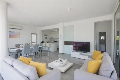 a living room with white furniture and yellow pillows at Protaras Olivine Villa Ol01 in Paralimni
