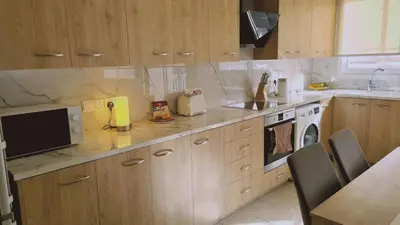 a kitchen with wooden cabinets and a sink and a microwave at STAY Mermaid's Cove in Limassol