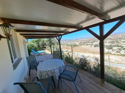 a patio with a table and chairs on a deck at Sunset Retreat Cyprus in Pendakomo