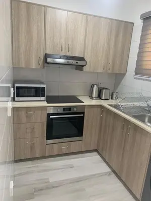 a kitchen with wooden cabinets and a stove top oven at Prestige Worldwide Apartments in Ayia Napa