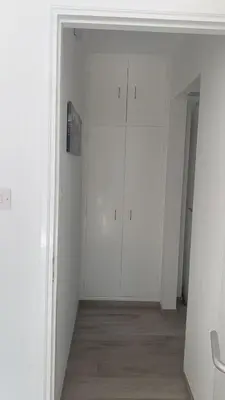 a white room with white cabinets and a wooden floor at Prestige Worldwide Apartments in Ayia Napa