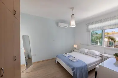a white bedroom with a bed and a window at Protaras Sunrise Zen Seafront Villa in Protaras