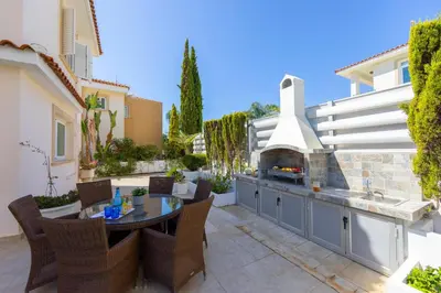 a patio with a grill and a table and chairs at Protaras Sunrise Zen Seafront Villa in Protaras