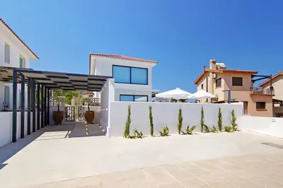 a white house with a white fence and trees at Votsalo Villa - 30m from Med Sea in Ayia Napa