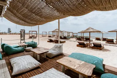 a beach with chairs tables and umbrellas on the beach at Votsalo Villa - 30m from Med Sea in Ayia Napa
