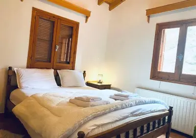 a bedroom with a bed with white sheets and a window at Vavatsinia Panorama Cottage in Vavatsinia