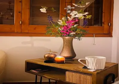 a vase of flowers on a table with a candle at Vavatsinia Panorama Cottage in Vavatsinia