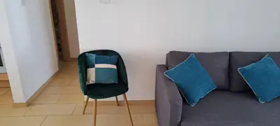 a gray couch with blue pillows and a chair at Nissi 3 Pool View Apartment in Ayia Napa