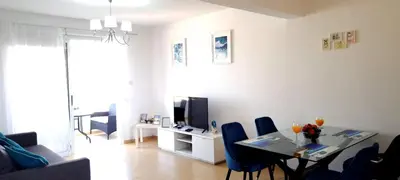 a living room with a table with chairs and a television at Nissi 3 Pool View Apartment in Ayia Napa
