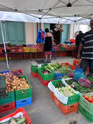 a market with many baskets of vegetables and people standing around at Alex Residence in Larnaka