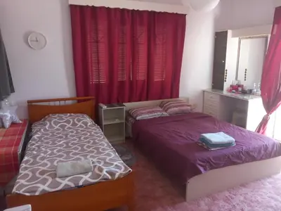 two beds in a bedroom with red curtains at Vasilis House family room in Larnaka