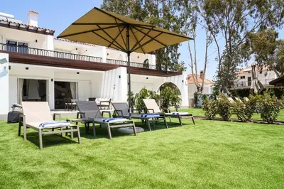a group of chairs and an umbrella on a lawn at Meneou Houses by the Sea in Larnaka