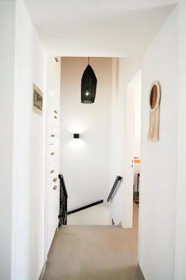 a hallway with white walls and a stairwell with a door and a pendant at Meneou Houses by the Sea in Larnaka